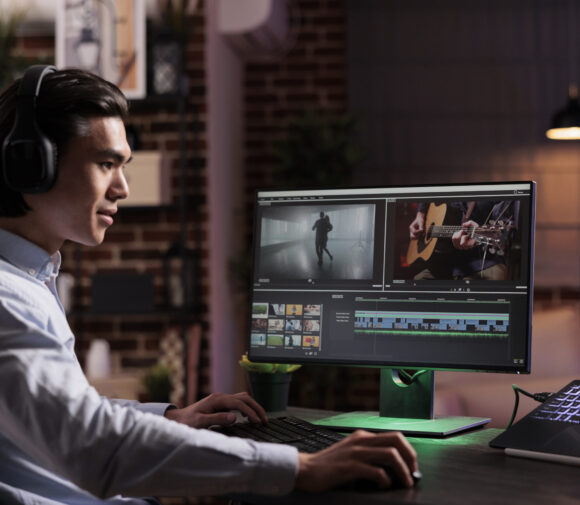 Male freelancer working on movie production with computer software, editing film montage with audio and visual effects. Creating multimedia content with footage, color grading creative app.